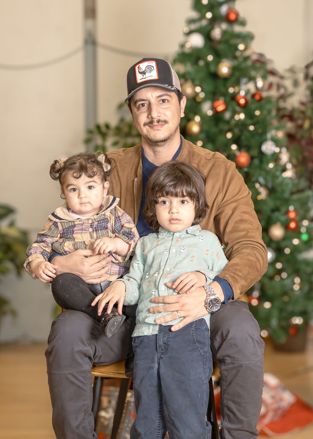 An adult and two children beside a Christmas tree