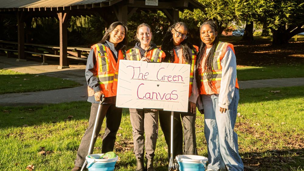 Four volunteers holding The Green Canvas sign
