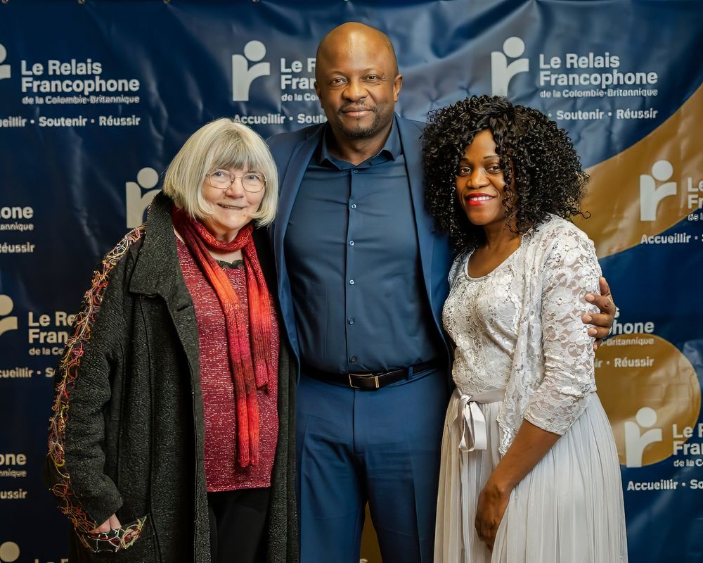 Three guests posing at the Le Relais Francophone photo backdrop