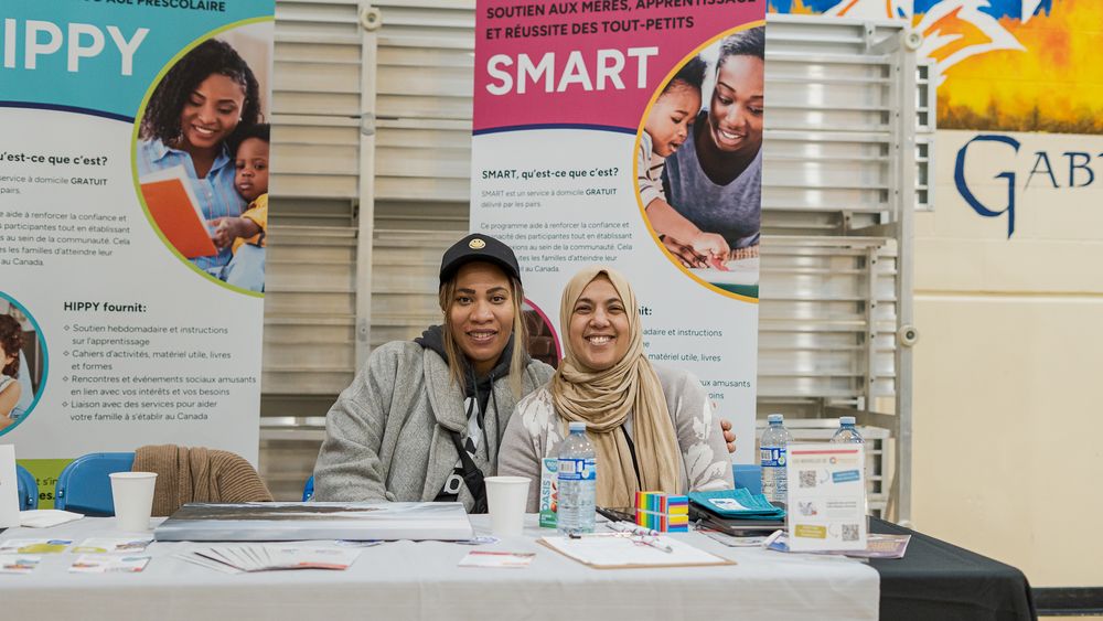 Two people smiling at a community resource table